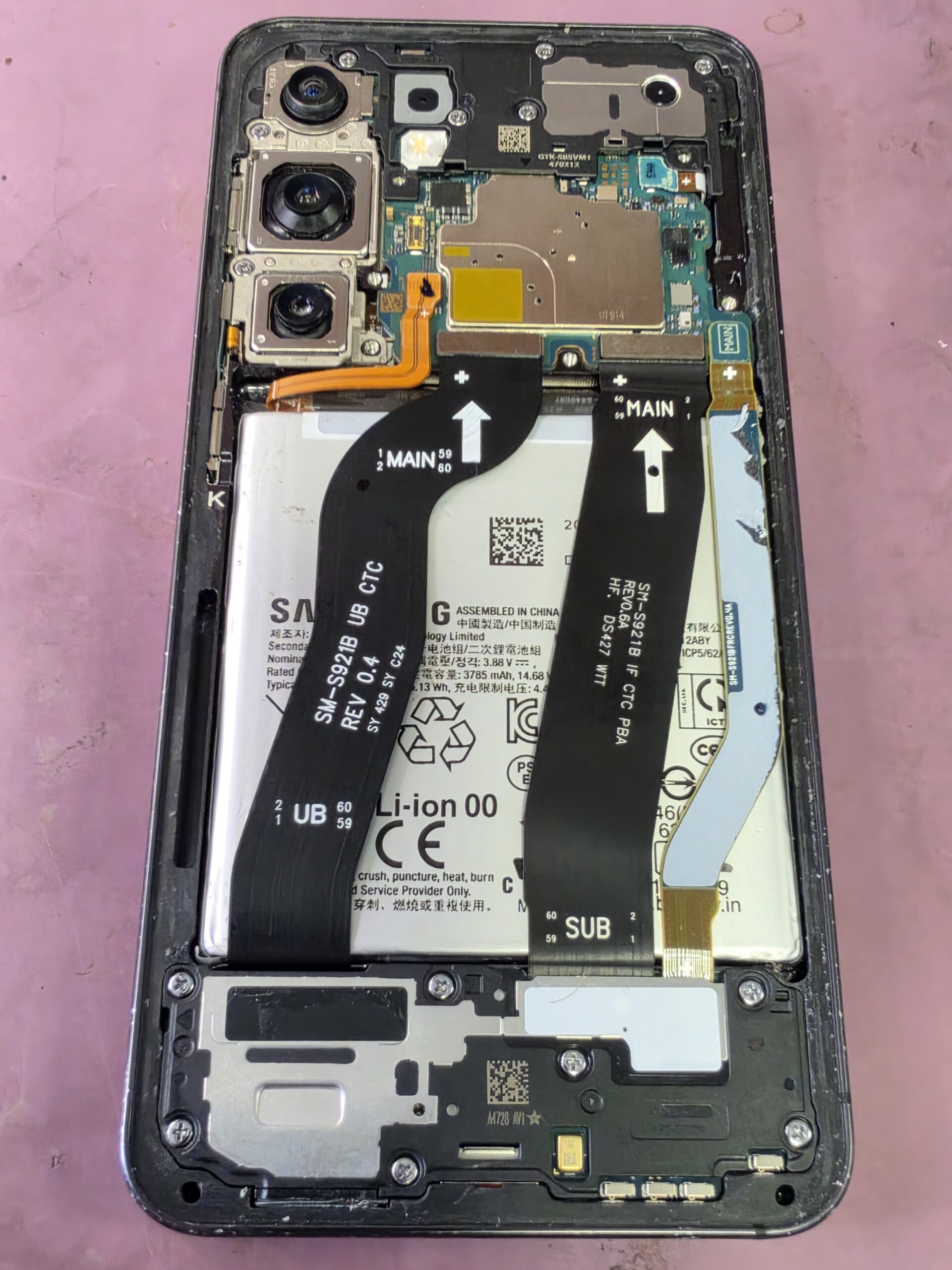 Genuine Samsung replacement battery fitted inside the opened Galaxy S24, beneath the internal ribbon cables