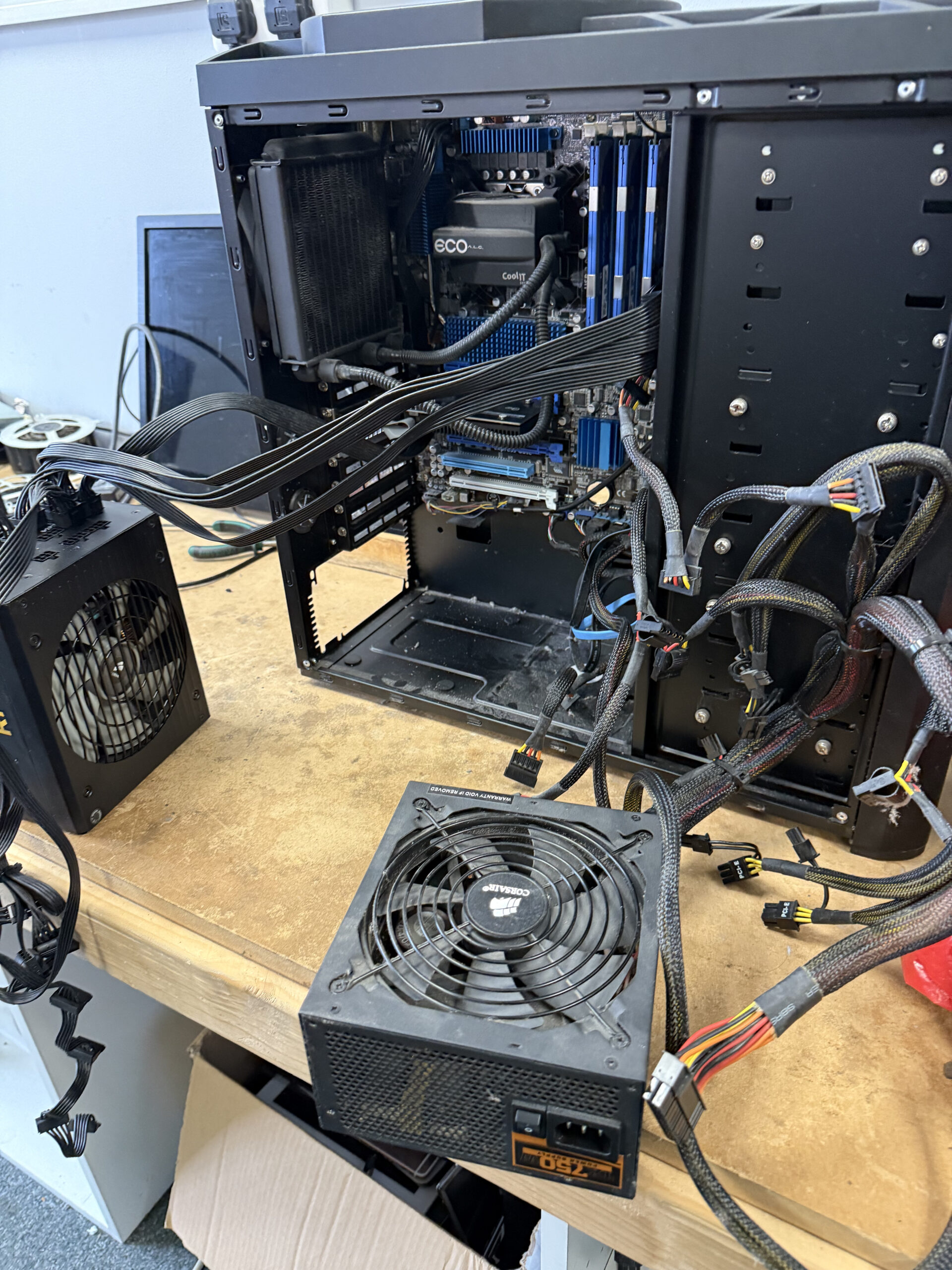 Desktop tower opened on the workbench with graphics card, cables and power supply units visible