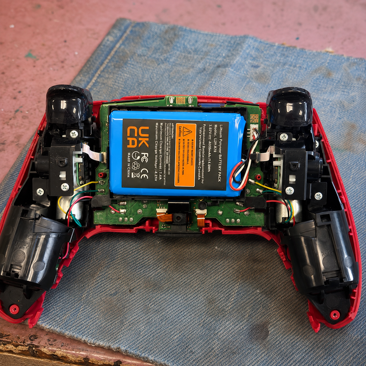 Opened red PS5 controller on the iPhoneBits workshop bench in Glengormley