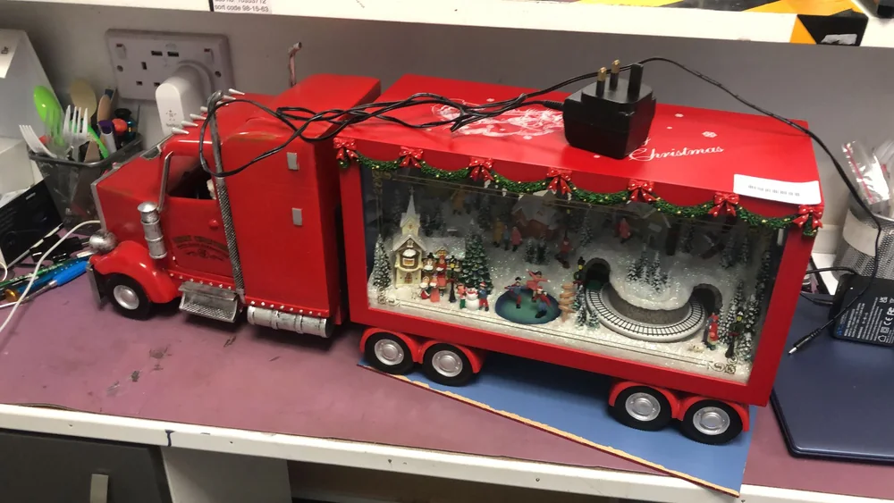 Electronic Christmas decoration shaped like a red lorry on the workshop bench