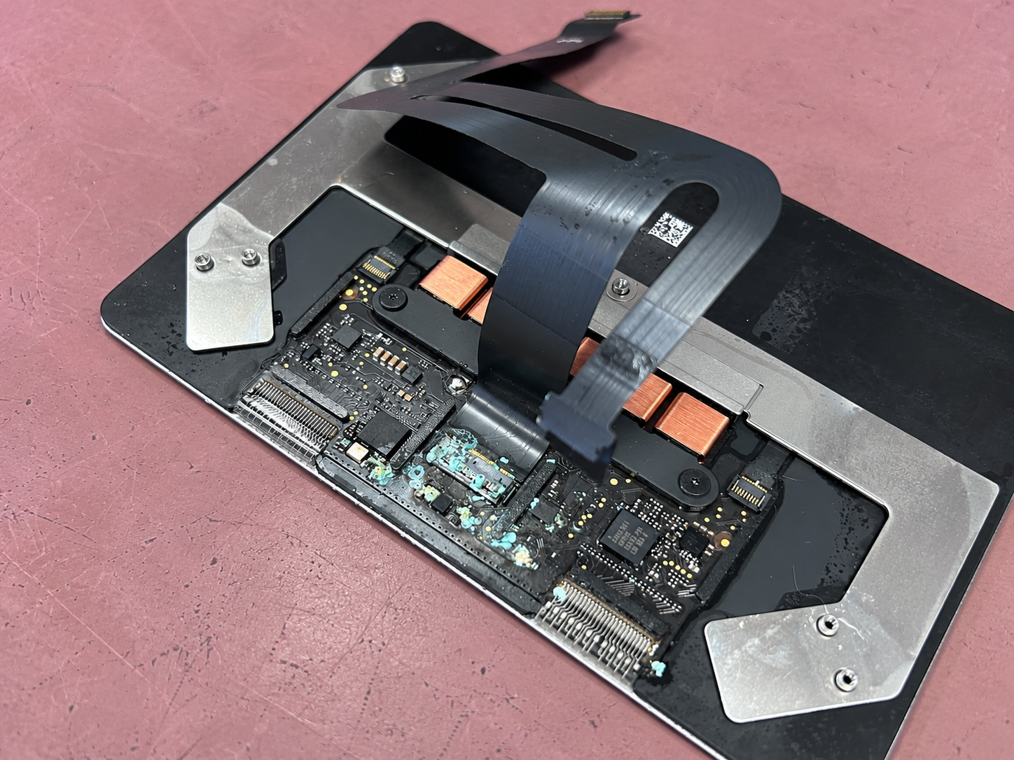Close-up of liquid-damage residue on the removed MacBook Air trackpad