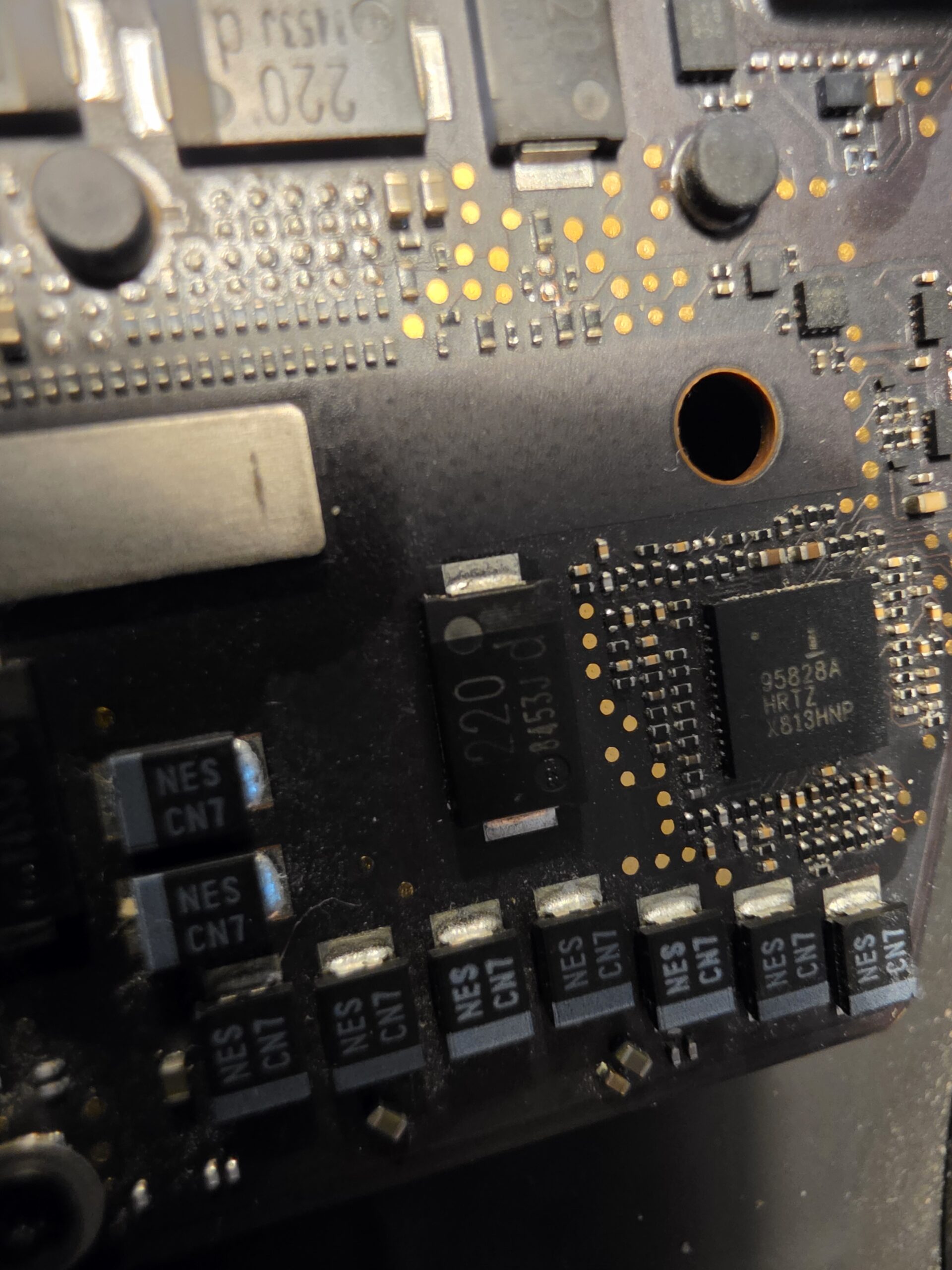 Close-up of MacBook logic board components during short-circuit diagnosis in Glengormley