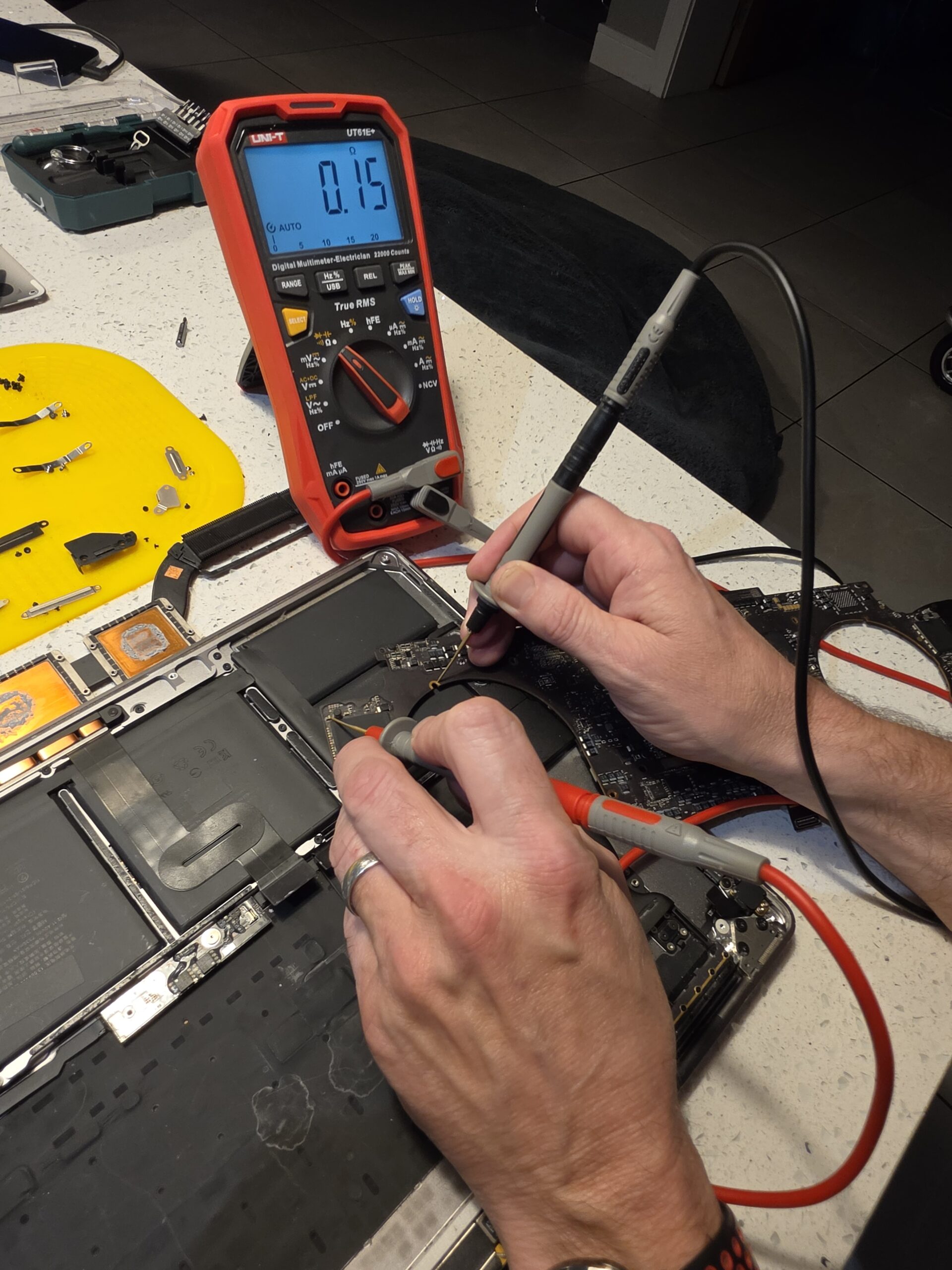 Belfast computer repair technician testing a MacBook A1990 logic board with multimeter probes
